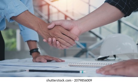 Two engineering man with construction worker greeting a foreman at renovating apartment. Engineering objects on workplace with partners interacting on background