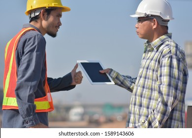 Two Engineering Use Tablet Working Road Construction Talking Project Management On Work Site