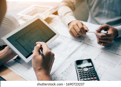 Two engineering working together and using digital tablet looking blueprint and analysis with architectural plan on desk. - Powered by Shutterstock - Get 15% off with code: PIKWIZARD15