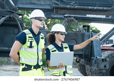 Two engineers are collaborating outdoors on construction site, pointing at vehicle with laptop. workers are focused and engaged, illustrating teamwork and technical support during refinery project.