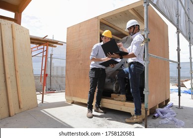 Two engineers are inspecting the machines in the container to make sure they meet the specifications before they are installed.