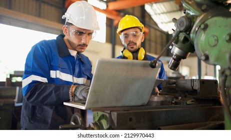 Two engineers man standing in front of equipment in CNC metal machine factory. Manager looking at tablet and see information how to fix the equipment and explain detail. Discuss and repair - Shutterstock ID 2129970443