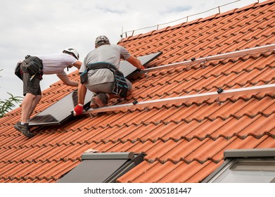 Two engineers on the house roof assemble photovoltaic panel. - Shutterstock ID 2005181447