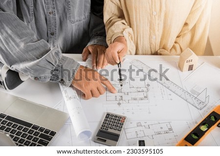 Two engineers pointing at drawings project, Architect team meeting consult and work for architectural construction project working with partner and engineering after editing on blueprint paper plans