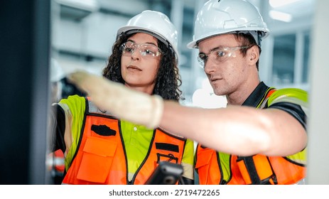 Two engineers program an industrial robot or CNC machine using an AI interface. The team manufactures advanced microchips or high tech components in a smart factory.