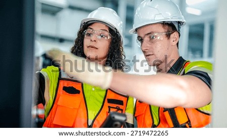 Two engineers program an industrial robot or CNC machine using an AI interface. The team manufactures advanced microchips or high tech components in a smart factory.