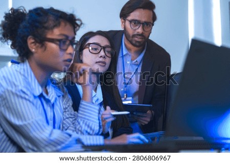Two engineers seen from behind studying source code on large monitors facing a wall of monitors filled with source code. The close-up captures modern software development, modernoffice.