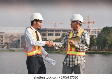 Two engineers shake hands at a building project.