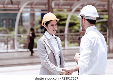 Two engineers shaking hand after a successful projects. Handsome white male engineer shaking hand with female engineer outdoor portrait. Young engineering career concept.