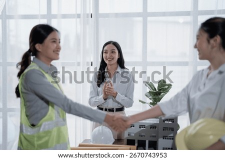 Two engineers shaking hands after a successful meeting, concluding a project, with their manager clapping hands, celebrating the agreement in the office