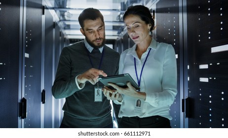 Two IT Engineers Walking in Data Center / Server Room, Talking, Running Diagnostics with Tablet Computer.