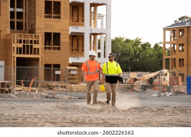 two engineers walking through a construction site. Construction industry engineering. Structural engineer and worker with touch pad discuss, plan working for the outdoors building construction site