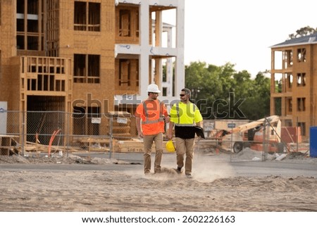 two engineers walking through a construction site. Construction industry engineering. Structural engineer and worker with touch pad discuss, plan working for the outdoors building construction site