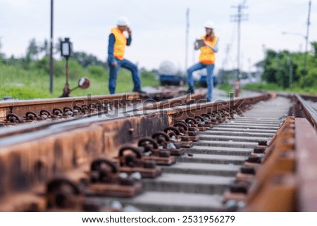Two engineers wearing safety gear and clothing inspect the tracks of a natural gas transport train. Focus on the railroad spikes.Rail Maintenance, Logistics, and Industrial Transportation