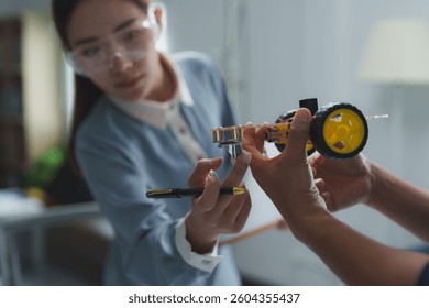 Two engineers are working together, assembling and testing a small robot prototype, demonstrating teamwork and innovation in a technology development setting