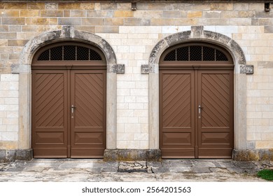 Two entrances, two brown wooden doors against a stone block wall. From the series of doors of the World. - Powered by Shutterstock