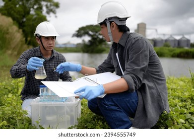 Two Environmental Engineers Inspect Water Quality and Take Water sample notes in The Field Near Farmland, Natural Water Sources maybe Contaminated by Toxic Waste or Suspicious Pollution Sites. - Shutterstock ID 2394555749