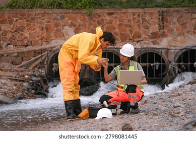 Two environmental field workers in protective gear conduct a water pollution inspection at a drainage outlet, collecting samples and analyzing data for contamination levels.