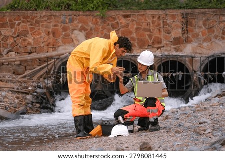 Two environmental field workers in protective gear conduct a water pollution inspection at a drainage outlet, collecting samples and analyzing data for contamination levels.