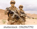 Two equipped and armed special forces soldiers standing in the desert. Concept of military anti-terrorism operations, special operations of NATO forces.