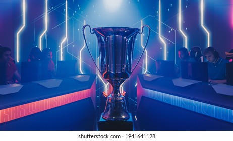 Two Esport Teams of Pro Gamers Play to Compete in Video Game on a Championship. Stylish Neon Cyber Games Online Streaming Tournament Arena with Trophy in the Center. - Shutterstock ID 1941641128