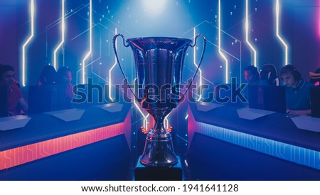 Two Esport Teams of Pro Gamers Play to Compete in Video Game on a Championship. Stylish Neon Cyber Games Online Streaming Tournament Arena with Trophy in the Center.