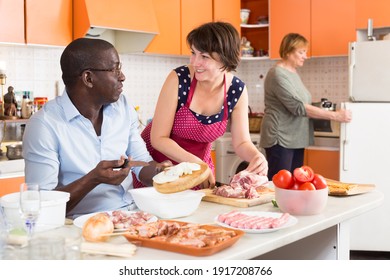 Two European Women And African American Man Cooking Together At Kitchen