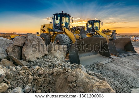 Two excavators moving stone and rock in a construction site