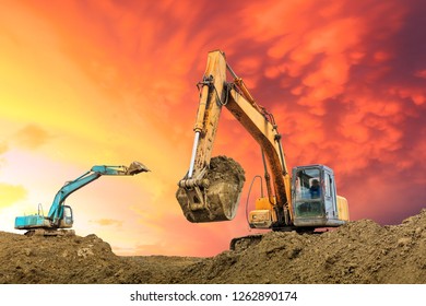 Two excavators work on construction site at sunset