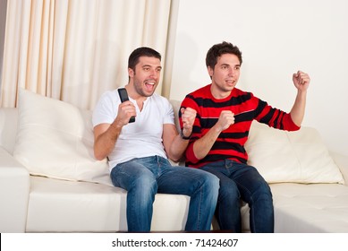 Two Excited Men Sitting On Couch And Watching Favorite Team Soccer With Goal