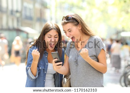 Similar – Two women laughing looking at their smart phone