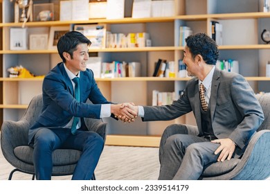 Two executive men shaking hands in lobby. - Powered by Shutterstock