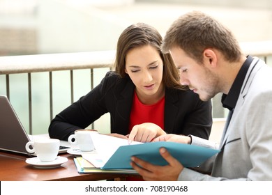 Two Executives Coworking Analyzing Documents Sitting In A Bar