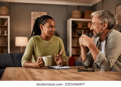 Two experienced individuals are deep in conversation while enjoying a comforting drink at their home table.