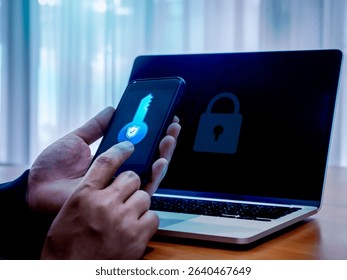 Two factor authentication or 2FA concept. Safety shield digital key icon on smart mobile phone screen in man hands while using laptop computer with padlock on display, cyber security technology.