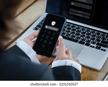 Two factor authentication or 2FA and cyber security concept. Shield icon and numbers on smartphone screen in hand, access password to laptop, identity verification with PIN verification code number.