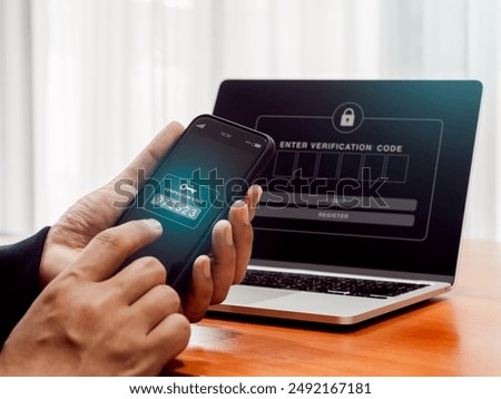 Two factor authentication or 2FA, cyber security concept. Password numbers with key icon for verification code on mobile smartphone screen holding by businessman hand who working with laptop computer.