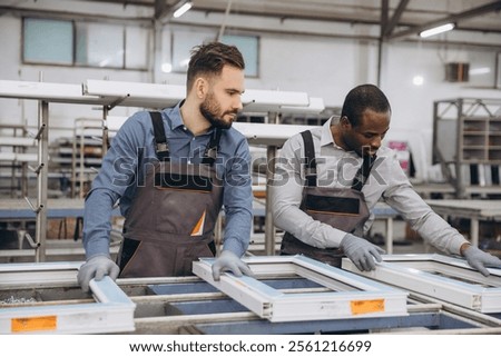 Two factory workers assembling pvc windows in a production line, working together on quality control in a modern window manufacturing plant