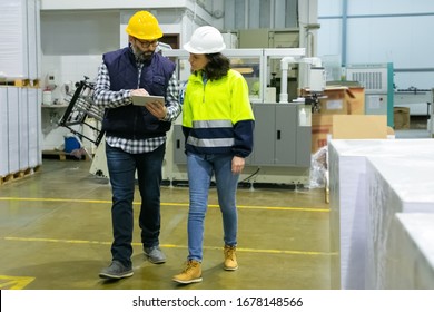 Two Factory Workers With Tablet Walking At Factory. Concentrated Employees Reading Information From Tablet. Print Manufacturing, Technology Concept