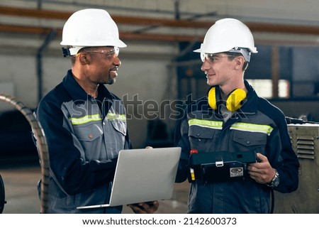 Two factory workers using adept machine equipment in a workshop . Industry manufacturing and engineering technology concept .
