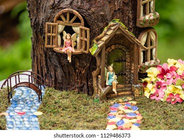 Two fairys sitting in front of their fairy house