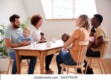 Two Families With Babies Meeting And Talking Around Table On Play Date At Home