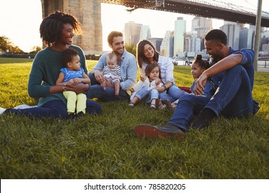 Two Families With Daughters Sitting On Lawn