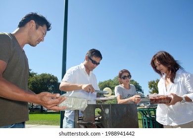 Two Families Enjoying BBQ In The Park