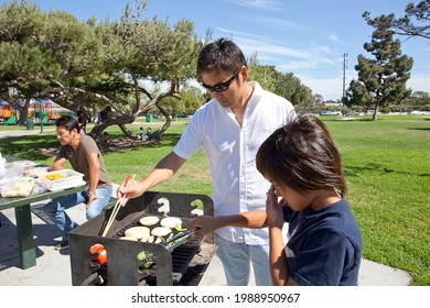 Two Families Enjoying BBQ In The Park