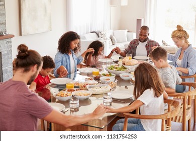 Two Families Praying Before Enjoying Meal At Home Together - Powered by Shutterstock