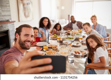 Two Families Taking Selfie As They Enjoy Meal At Home Together