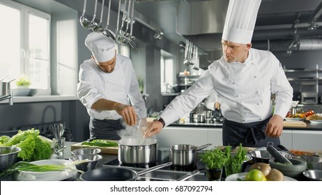 Two Famous Chefs Work as a Team in a Big Restaurant Kitchen. Vegetables and Ingredients are Everywhere, Kitchen Looks Modern with Lots of Stainless Steel. - Powered by Shutterstock