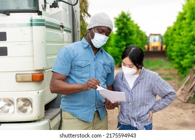 Two Farm Workers In Face Masks For Disease Protection Discussing Papers Standing Near Car At Outdoors