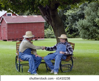 Two Farmers In Bib Overalls Shaking Hands Sitting In Lawn Chairs